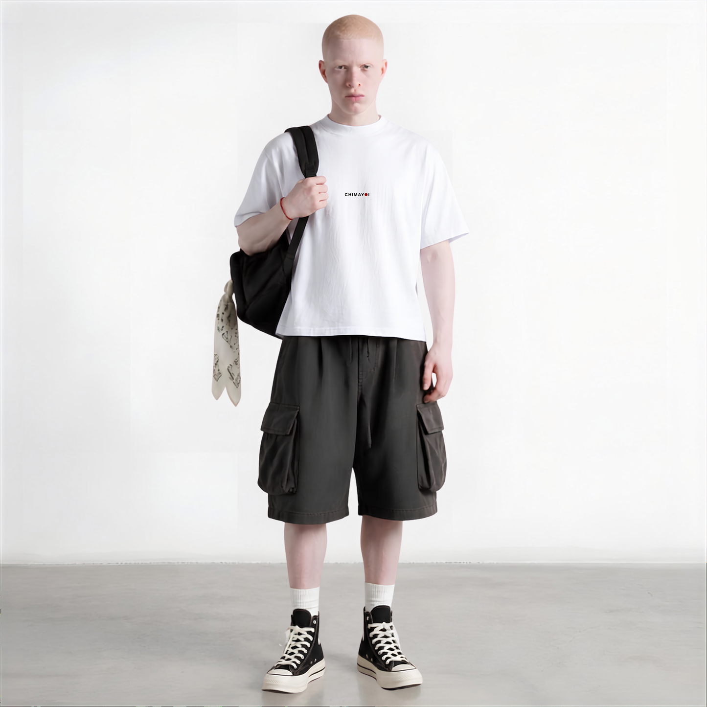 Male model wearing CHIMAYOI White quiet luxury tee with dark shorts in a minimalist studio setting.