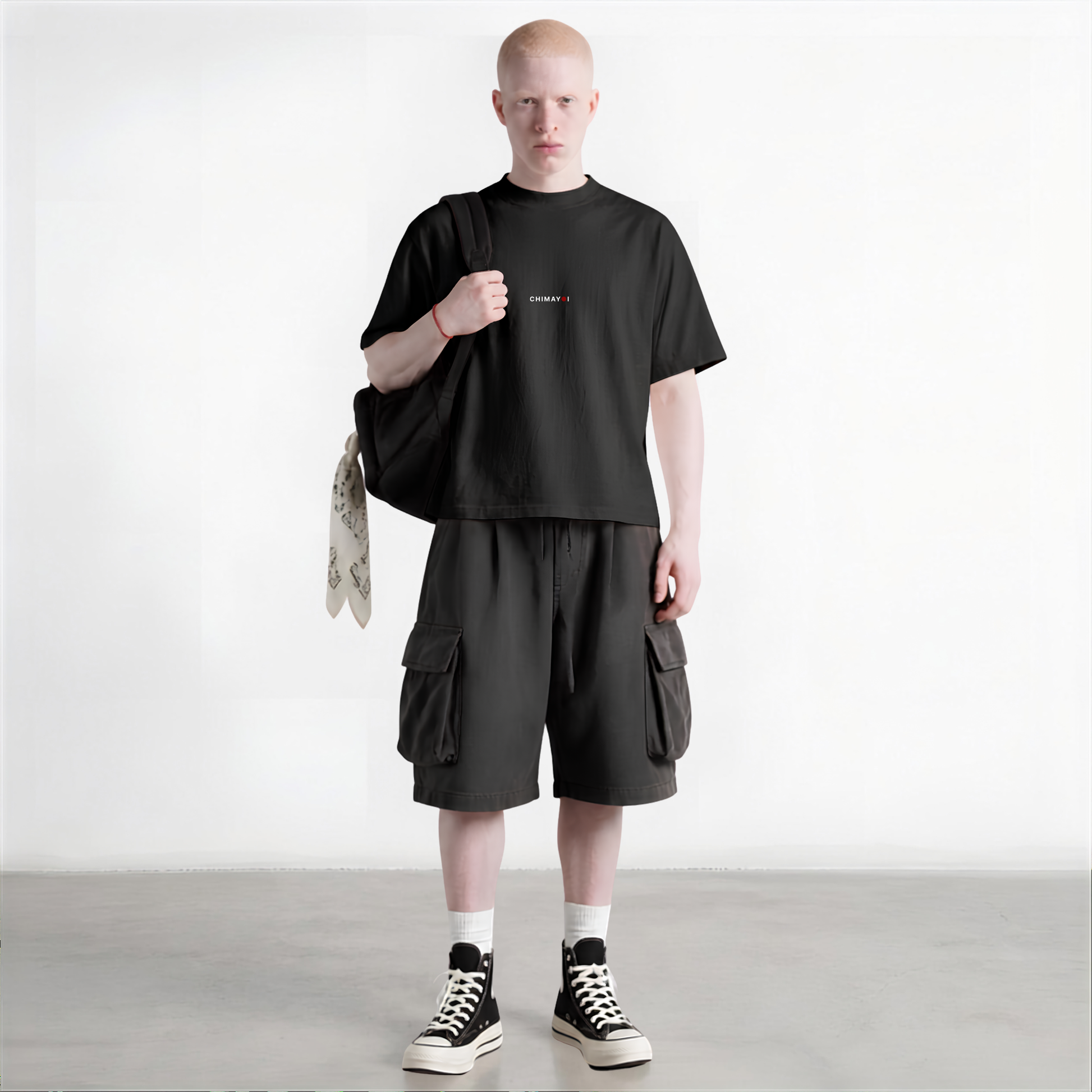 Male model styling the CHIMAYOI Black minimalist heavyweight tee with relaxed shorts and casual streetwear accessories.